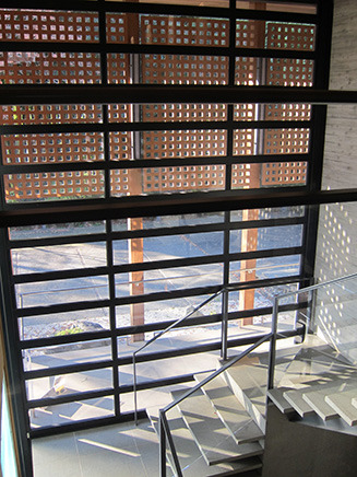 2階から眺めた階段の踊り場。
下半分がガラス、上部はガラスの周りに木を施すことで、
光が差し込むとコンクリートの階段部分に
“光のモザイク”が表れるように設計されている。