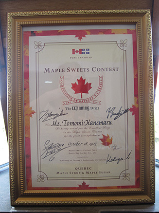 トロフィーの隣には、カナダのメープルシロップとメープルシュガーを使った
「メープルスイーツコンテスト」が2013年10月28日に開催され、カナダ大使館で行われた表彰式で、
 当時ポンパドウルのシェフとして参加した金丸さんが受け取った賞状も並ぶ。