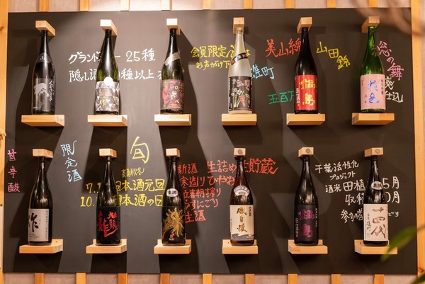 壁際に店主お薦めの日本酒の酒瓶がディスプレイされている。