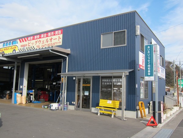 青色の建物。アーセナル通り沿いにあり、道を挟んだ向かい側には「8代葵カフェ 市川店」がある。