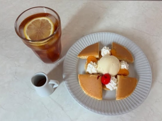 Pioのおすすめセット「ドリンク(アイスティ)とホットケーキ」(900円)。ホットケーキにはアイスクリームと生クリームとフルーツがトッピングされている。